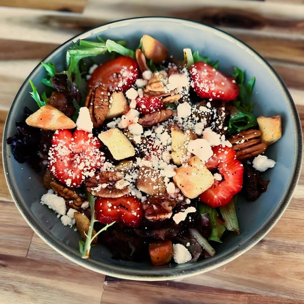 A vibrant Coco Mexican Restaurant salad with strawberries, pecans, croutons, and crumbled cheese.